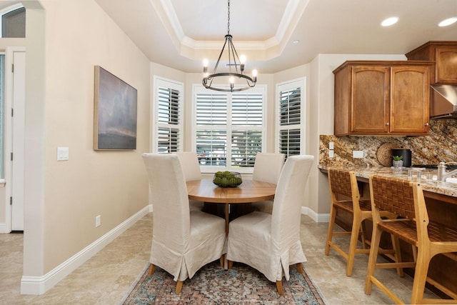 dining space with a tray ceiling, a notable chandelier, and ornamental molding