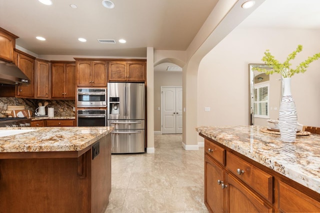 kitchen featuring sink, light stone countertops, stainless steel appliances, and decorative backsplash