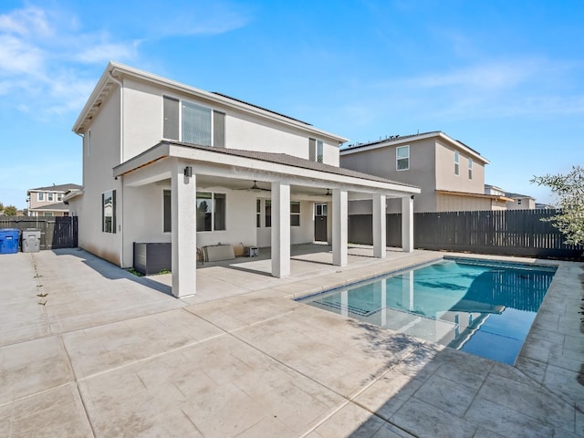 rear view of property featuring a fenced in pool, ceiling fan, and a patio area