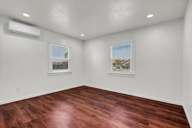 empty room featuring dark hardwood / wood-style flooring, a wealth of natural light, and a wall mounted air conditioner