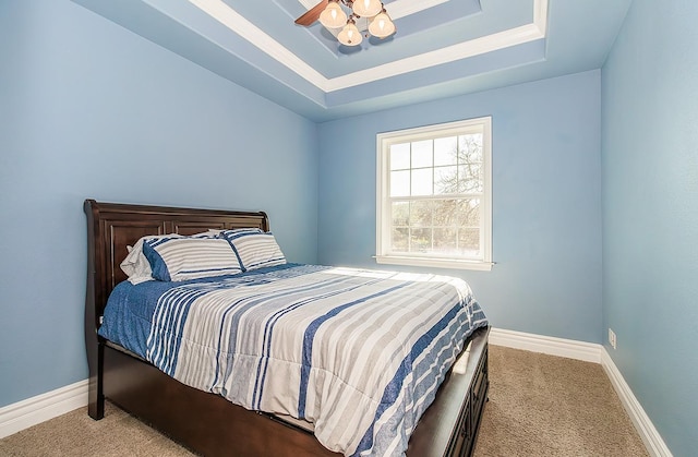 bedroom with light carpet, baseboards, and a tray ceiling