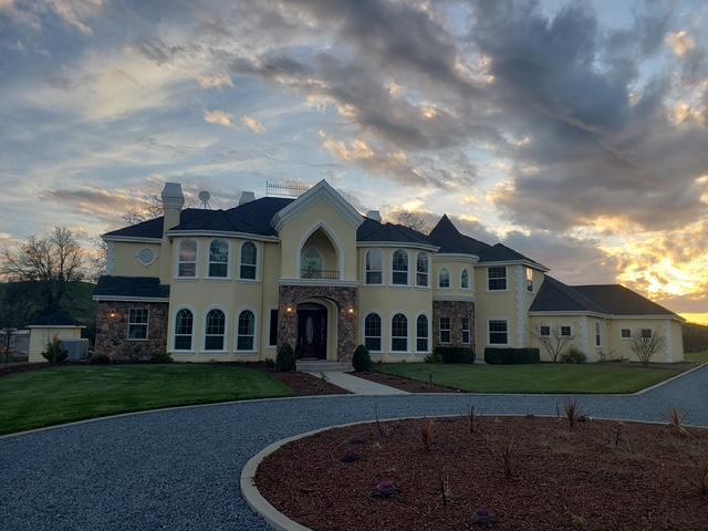 french country style house with stone siding, a lawn, a chimney, and stucco siding