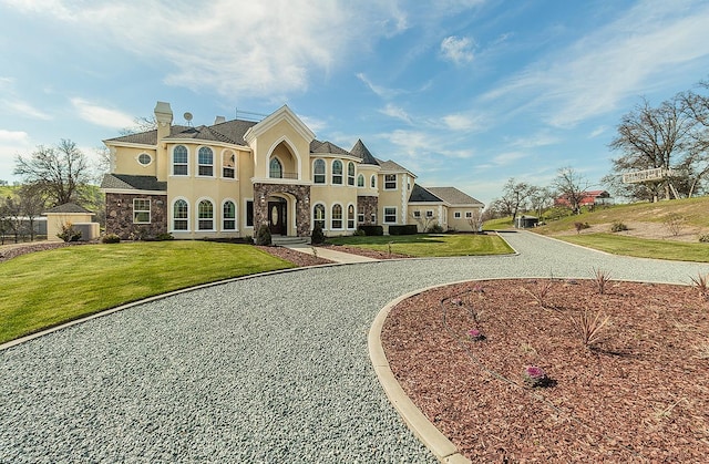 view of front of house with stone siding, a chimney, a front lawn, and stucco siding