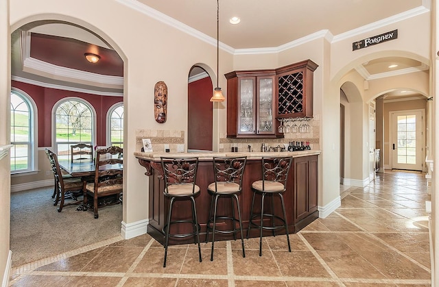 bar featuring ornamental molding, tasteful backsplash, decorative light fixtures, and baseboards