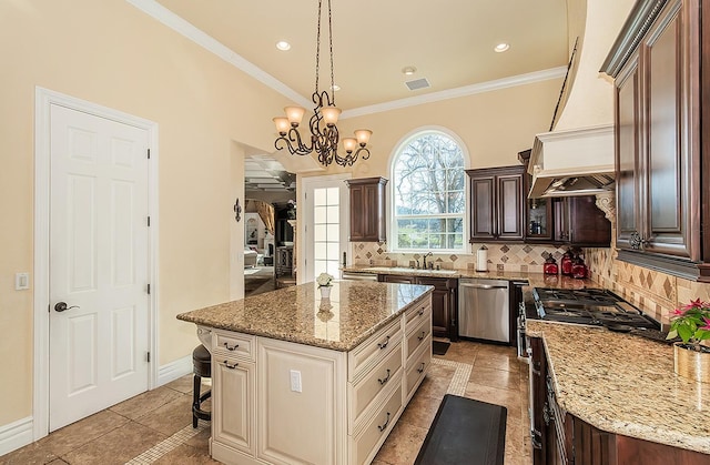 kitchen featuring a kitchen island, ornamental molding, backsplash, stainless steel appliances, and a sink