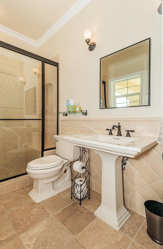 full bath with a stall shower, toilet, a wainscoted wall, ornamental molding, and tile walls