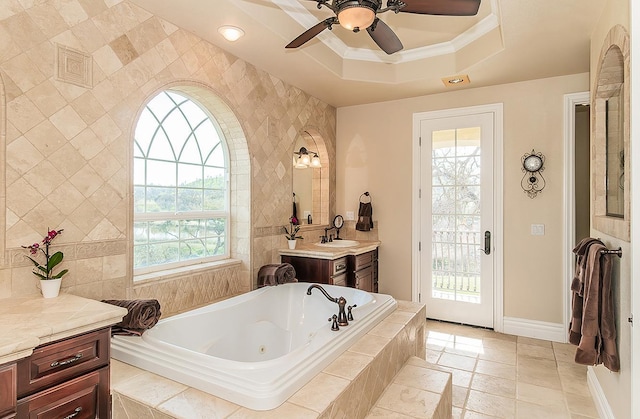 full bath featuring vanity, baseboards, a tray ceiling, a tub with jets, and crown molding