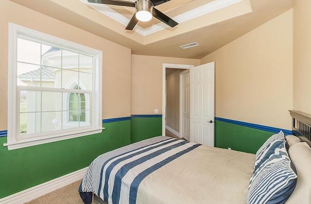 bedroom featuring carpet flooring, visible vents, baseboards, a ceiling fan, and a tray ceiling