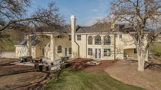 rear view of house featuring a patio area, stucco siding, a lawn, and french doors