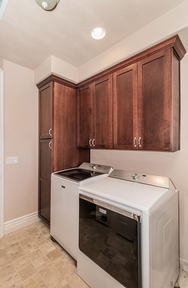 washroom with cabinet space, baseboards, and washing machine and clothes dryer