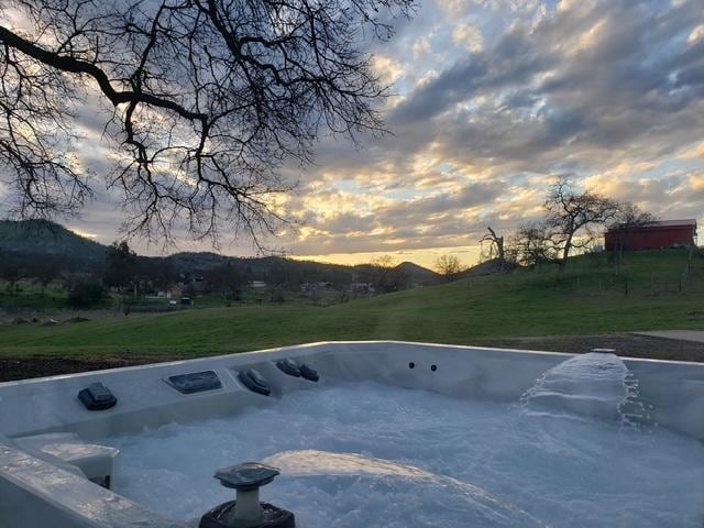 view of pool featuring a yard, a hot tub, and a mountain view