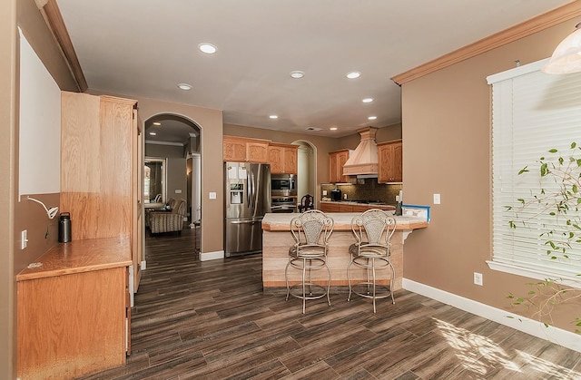 kitchen with a breakfast bar, a peninsula, custom exhaust hood, stainless steel appliances, and light countertops