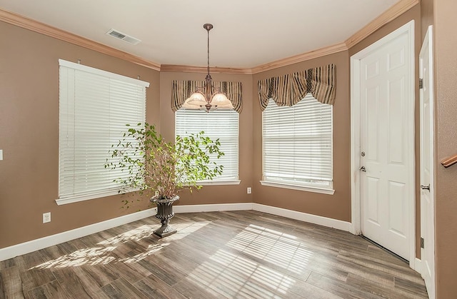 unfurnished dining area featuring ornamental molding, visible vents, a notable chandelier, and baseboards