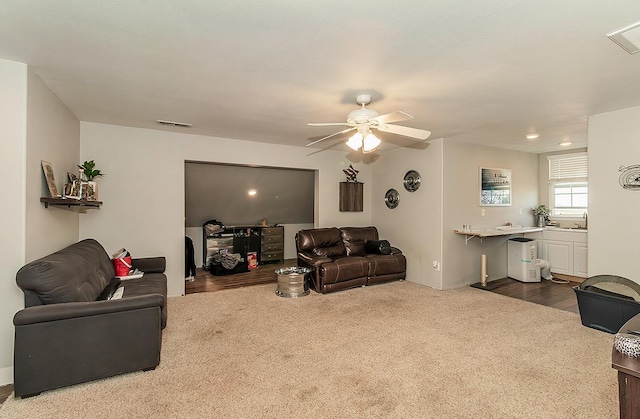 living area featuring ceiling fan, dark colored carpet, and visible vents