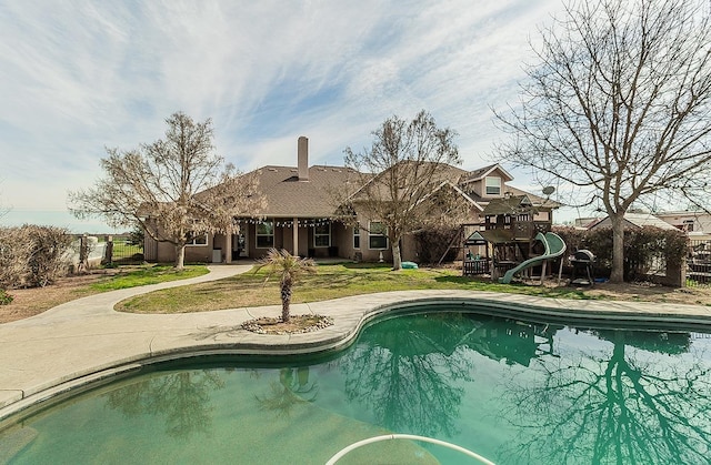 outdoor pool featuring a lawn, a playground, and fence