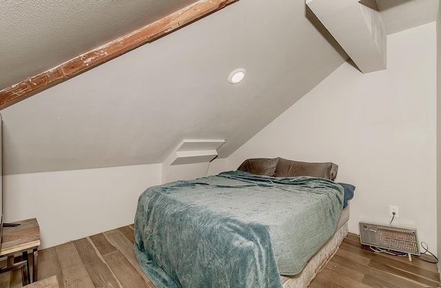 bedroom featuring vaulted ceiling with beams and wood finished floors