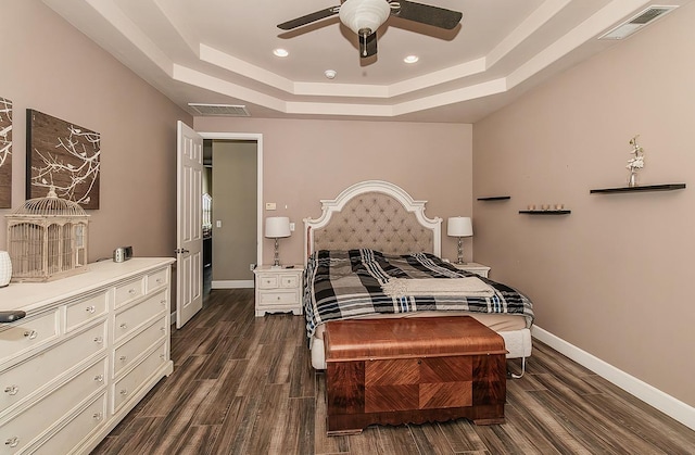 bedroom featuring baseboards, visible vents, a tray ceiling, and dark wood-type flooring