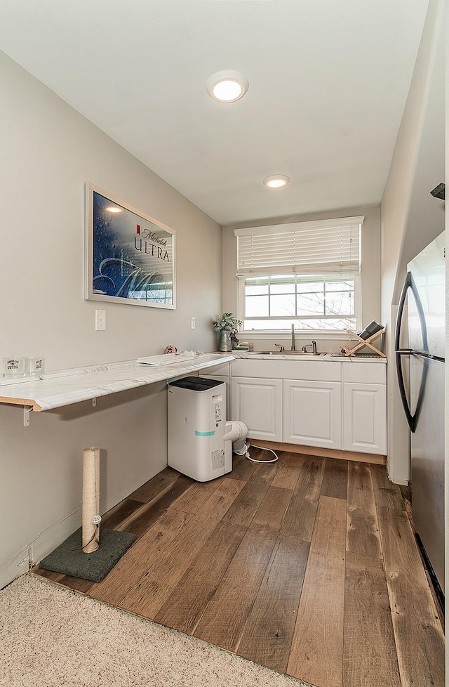 kitchen featuring dark wood finished floors, light countertops, freestanding refrigerator, white cabinetry, and a sink