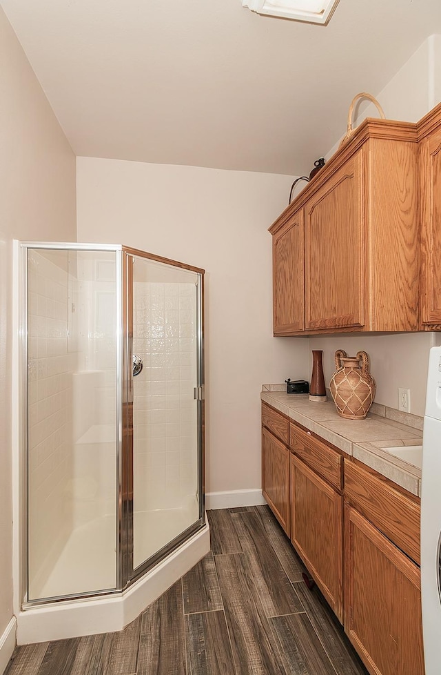 interior space featuring vanity, a shower stall, baseboards, and wood finished floors