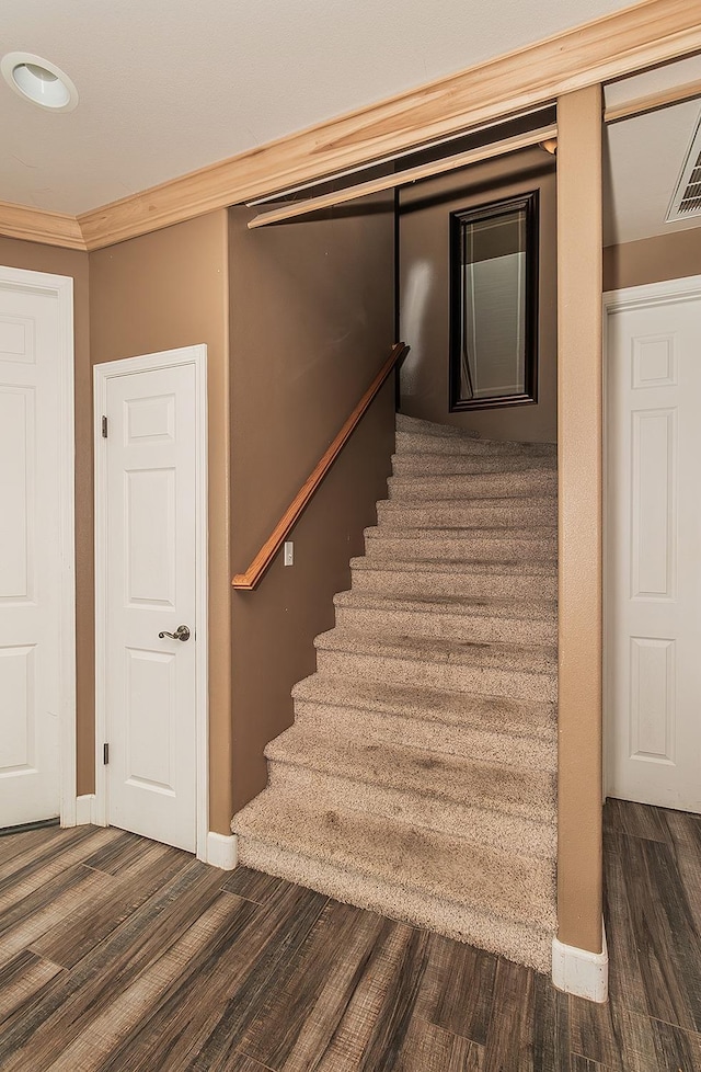 stairway featuring crown molding, baseboards, and wood finished floors