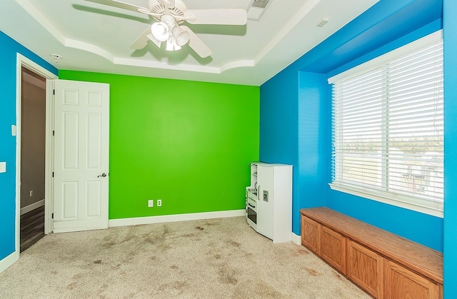 unfurnished bedroom featuring baseboards, visible vents, a tray ceiling, and light colored carpet