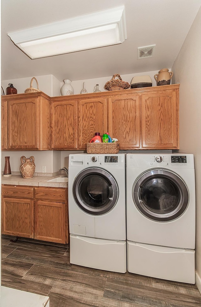 clothes washing area featuring dark wood-style floors, visible vents, cabinet space, a sink, and separate washer and dryer