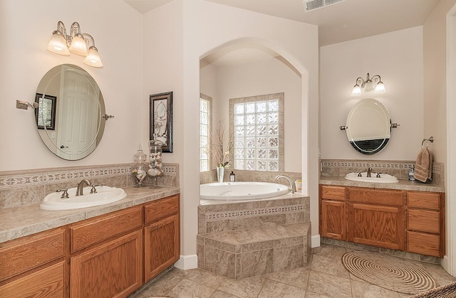 full bathroom with a garden tub, two vanities, a sink, and decorative backsplash