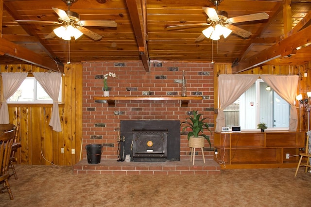 carpeted living room featuring wood walls, vaulted ceiling with beams, ceiling fan, and wood ceiling