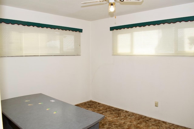 spare room with ceiling fan and dark carpet