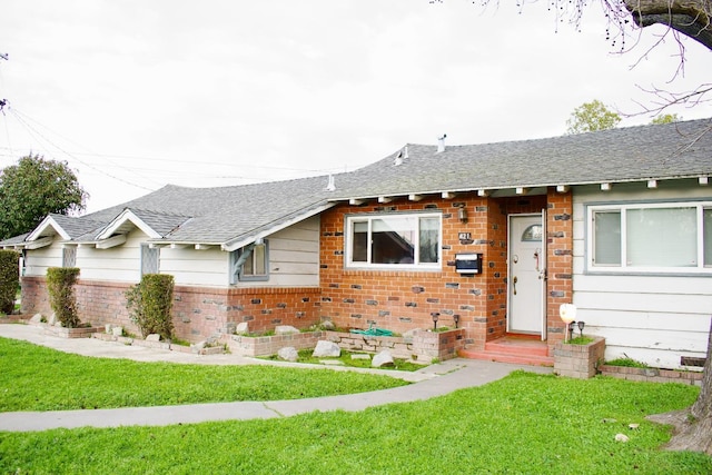 ranch-style house with brick siding, a front yard, and roof with shingles