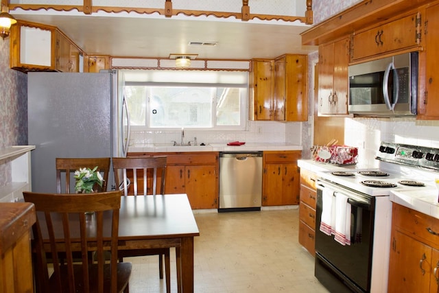 kitchen with tile counters, visible vents, stainless steel appliances, and brown cabinetry