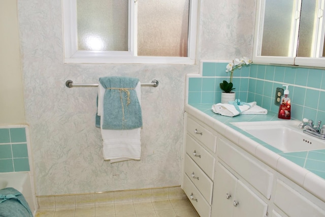 full bath featuring tile patterned floors, a tub to relax in, and vanity