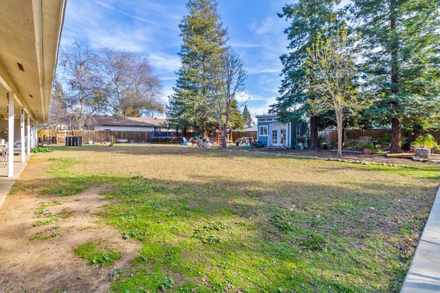 view of yard featuring a fenced backyard, central AC unit, and an outbuilding