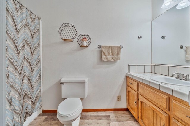 bathroom featuring curtained shower, toilet, wood finished floors, vanity, and baseboards