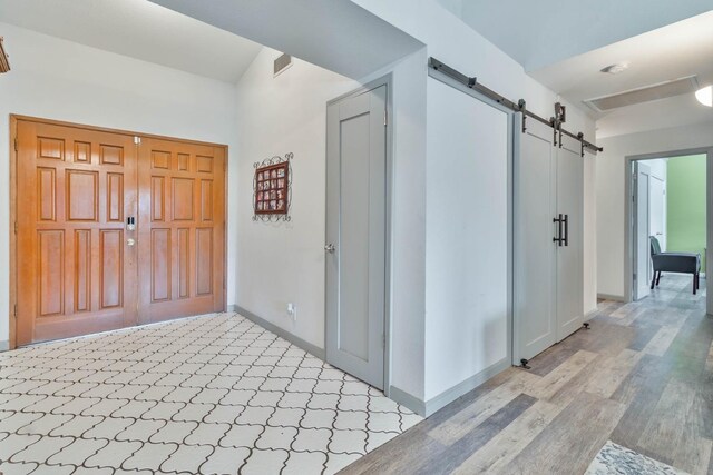 entrance foyer featuring light wood-style floors, baseboards, and a barn door