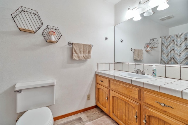 full bathroom with toilet, vanity, wood finished floors, baseboards, and visible vents