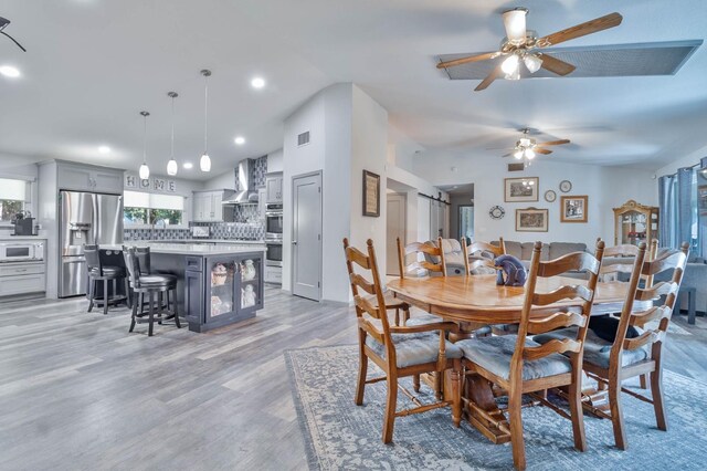 dining room with recessed lighting, visible vents, light wood-style floors, a ceiling fan, and vaulted ceiling