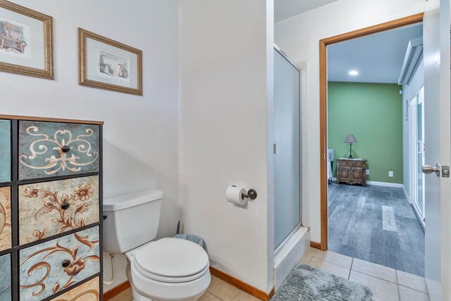 full bathroom with toilet, a shower stall, baseboards, and tile patterned floors