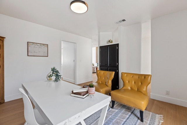 office space featuring light wood finished floors, baseboards, and visible vents