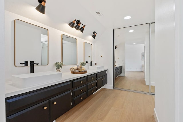 bathroom with double vanity, visible vents, a sink, and wood finished floors