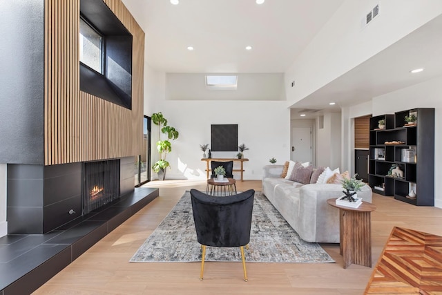 living area with recessed lighting, light wood-style flooring, visible vents, and a tile fireplace