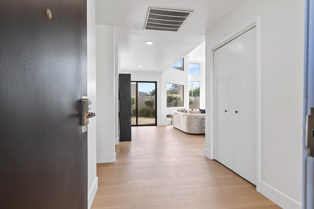 corridor featuring light wood-style floors, baseboards, and visible vents