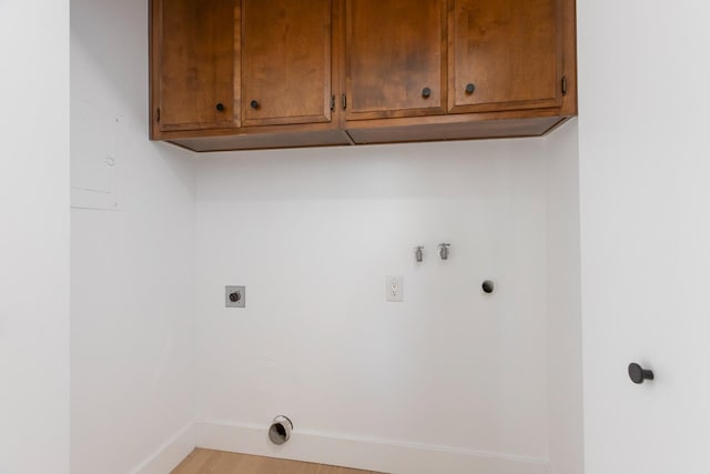 laundry area featuring cabinet space, light wood-style floors, hookup for an electric dryer, gas dryer hookup, and baseboards