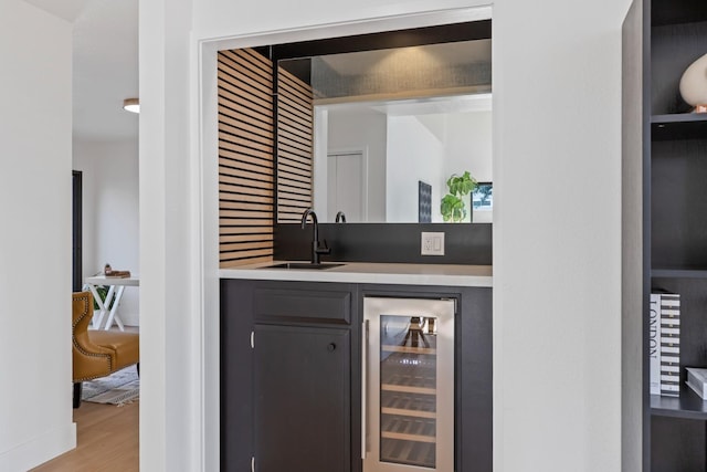 bar featuring beverage cooler, indoor wet bar, a sink, and wood finished floors