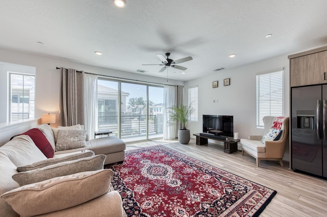 living area featuring light wood-style floors, plenty of natural light, and visible vents