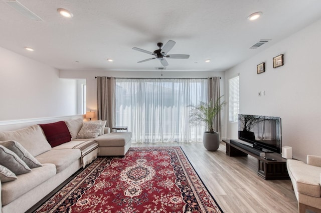 living room with a textured ceiling, recessed lighting, a ceiling fan, visible vents, and light wood-style floors