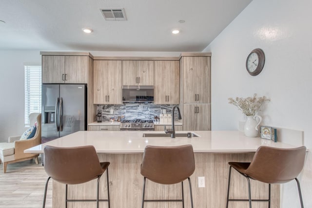 kitchen featuring a sink, visible vents, stainless steel refrigerator with ice dispenser, and light countertops