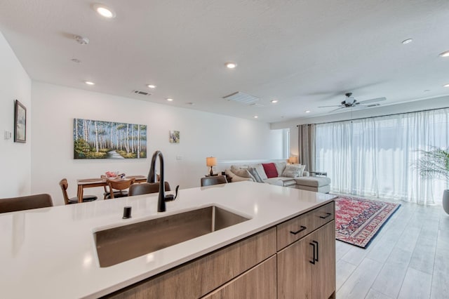 kitchen with a sink, open floor plan, light countertops, light wood-type flooring, and modern cabinets