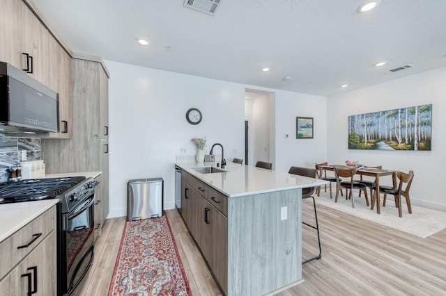 kitchen featuring a breakfast bar, light countertops, black gas stove, and visible vents