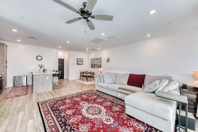 living room featuring light wood-style flooring, visible vents, and recessed lighting